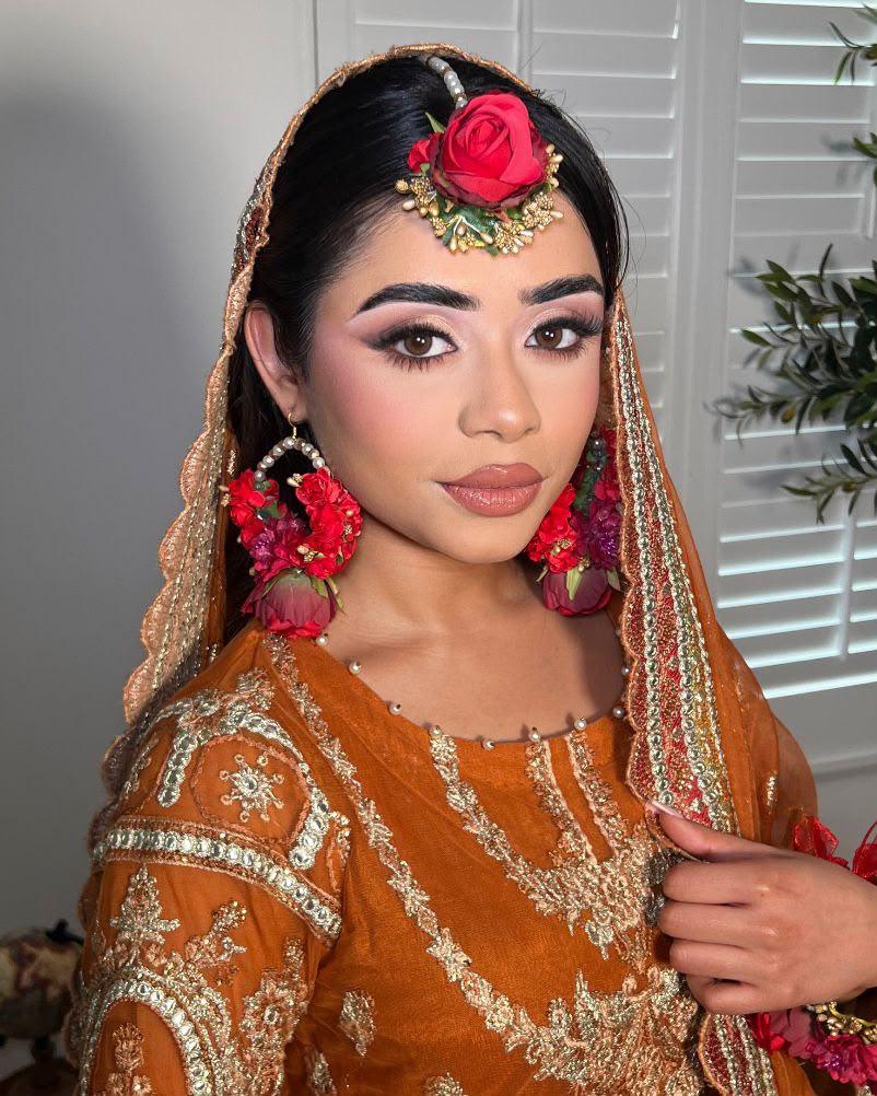 Mehndi bride with fresh red rose flowers set into the hair