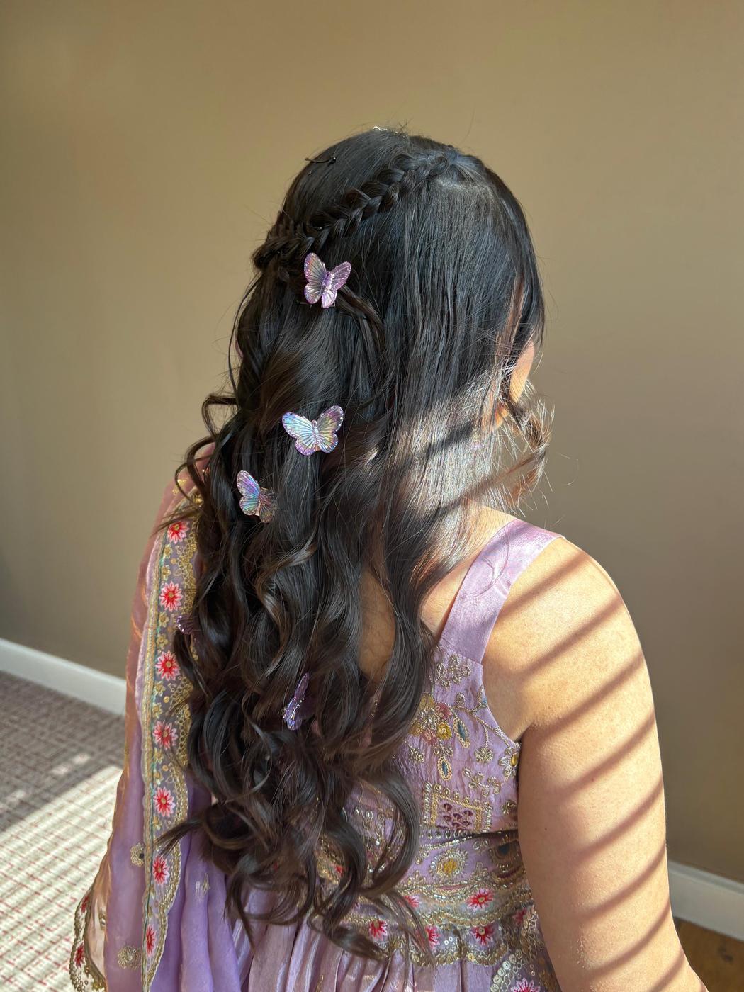 Young guest with a waterfall braid, soft curls and butterfly clips