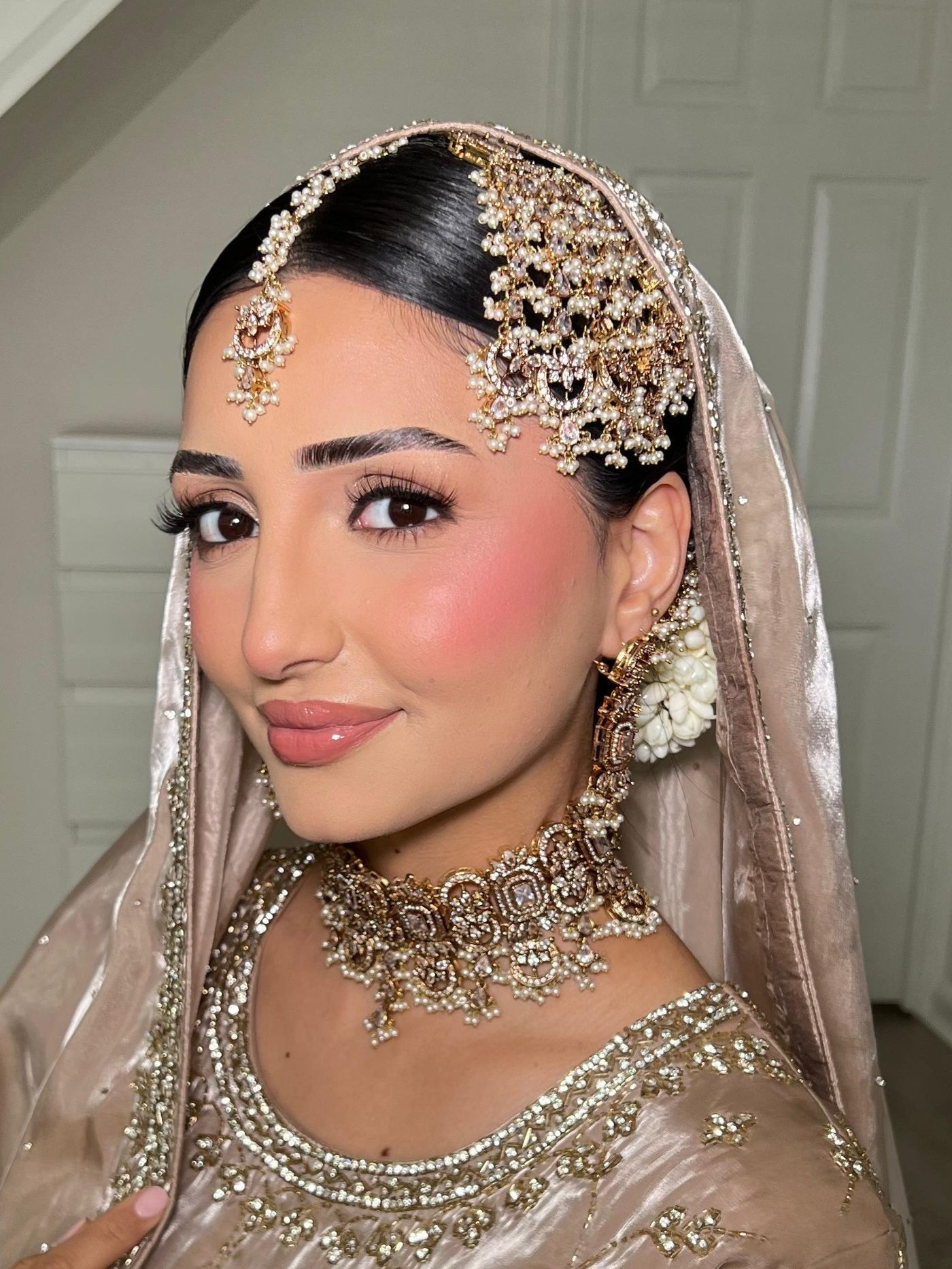 Bride with a sleek centre-parted style dressed with a pearl jhoomar and matha patti